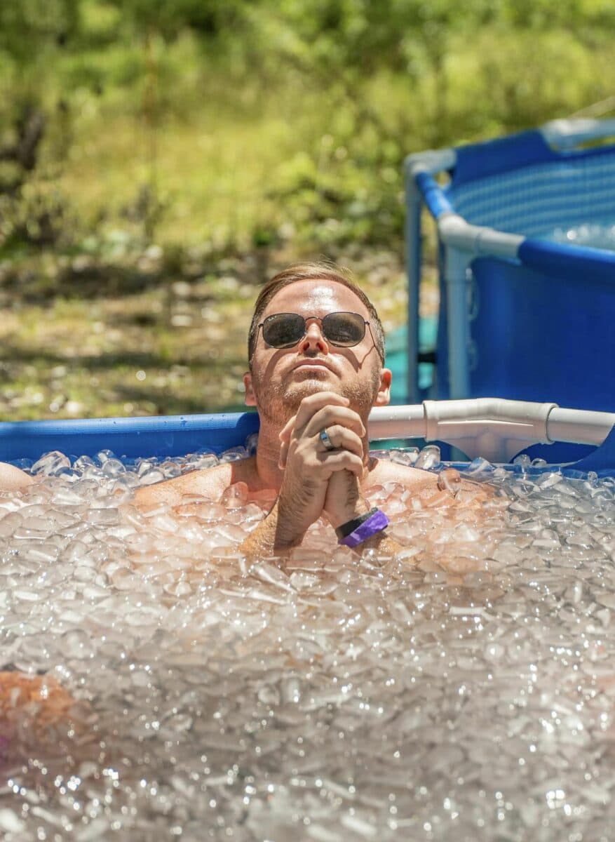 Sitting in an ice bath, hands pressed together, eyes up